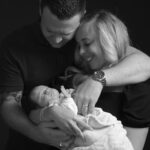 black and white image, close up family, mum dad baby, dad cuddles mum and baby, baby sleeps