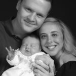 black and white image, close up family, mum dad baby looking at camera