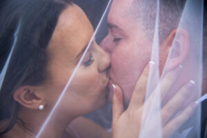 bride, hands on groom face, kissing, tenderness, under veil, eyes closed, side view, close up