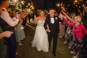 bride and groom wave, walking, onlookers, night time, sparklers
