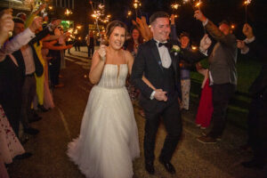 bride and groom wave, walking, onlookers, night time, sparklers