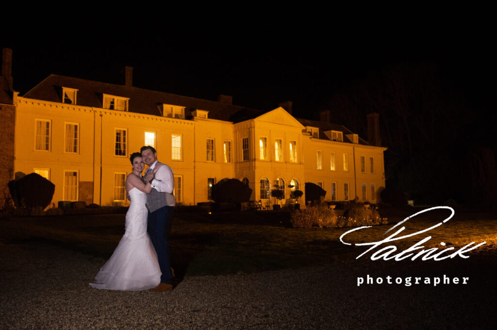 gosfield hall at night, bride and groom in foreground